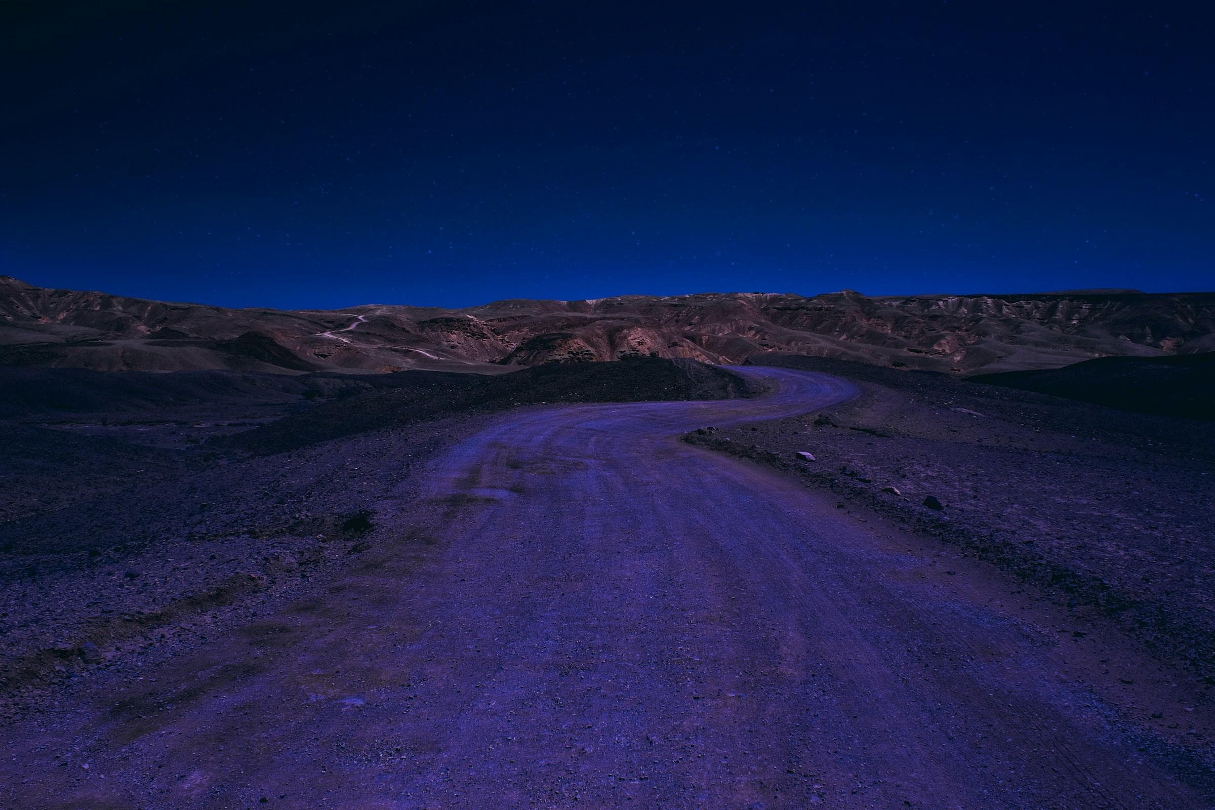 A desert road winding toward the mountains at dusk